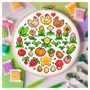 May include: A round cross-stitch embroidery hoop with a white background and colorful pixelated images of farm animals, crops, and other items. The hoop is surrounded by colorful embroidery floss.