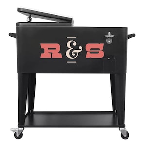 May include: Black metal cooler with the letters "R & S" in red and white. The cooler has a hinged lid, a bottle opener, and sits on a black metal stand with wheels. The cooler is designed for outdoor use.