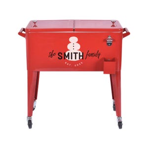 May include: A red metal cooler with the text "the SMITH family EST. 2025" and a snowman graphic. The cooler has a bottle opener, a small storage compartment, and is mounted on wheels.