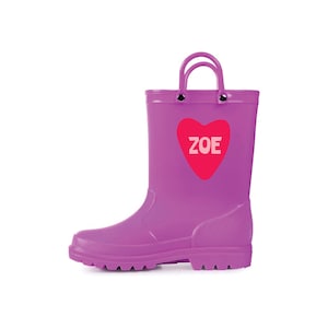 May include: A purple rain boot with a handle and a pink heart with the name "ZOE" in white. The boot is made of a shiny material and has a textured sole.