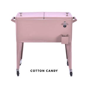 May include: A cotton candy pink metal cooler with a bottle opener and a small storage compartment. The cooler has two hinged lids, handles on the sides, and sits on four legs with wheels. The text "COTTON CANDY" is at the bottom.