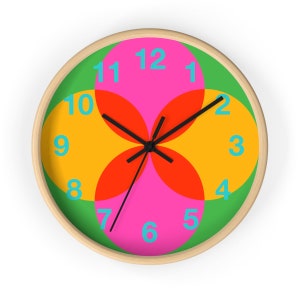 May include: A round wall clock with a green background and four overlapping circles in red, orange, and pink. The numbers 1 through 12 are in blue and are placed around the edge of the clock.