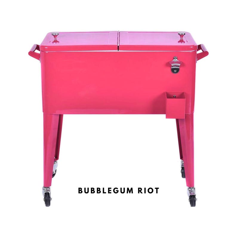 May include: A bubblegum pink metal cooler with a dual-lid design, handles, and a bottle opener. The cooler has a small storage compartment and sits on four caster wheels. The text "BUBBLEGUM RIOT" is printed on the front.