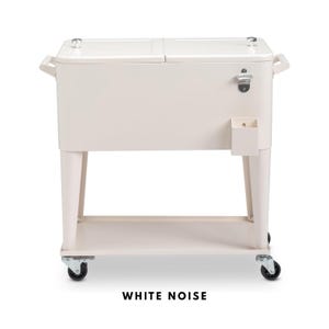 May include: Off-white rolling cooler with a bottle opener and a small storage compartment. The cooler has a two-part lid, handles, and a lower shelf. The text "WHITE NOISE" is printed at the bottom.