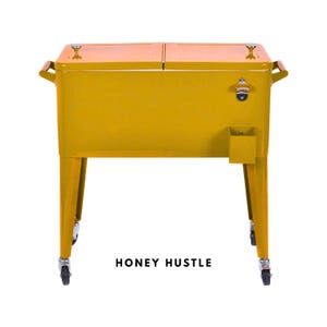 May include: A mustard yellow metal cooler with a hinged lid, wooden handles, and a built-in bottle opener. The cooler has four legs with wheels and the text "HONEY HUSTLE" at the bottom.