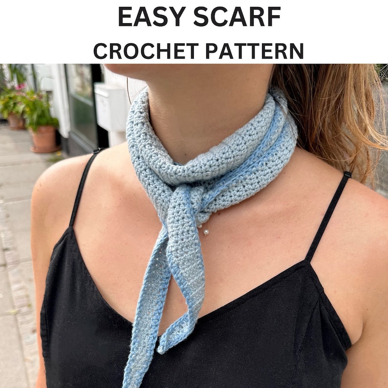 May include: A light blue crocheted scarf with a textured pattern. The scarf is tied around the neck of a person wearing a black tank top.