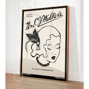 May include: A framed vintage-style print featuring a black and white illustration of a woman with stylized hair and a feather headpiece. The print includes the text "Mrs. C.J. Walker's Beauty Parlor" and the address "210 North Greenwood".