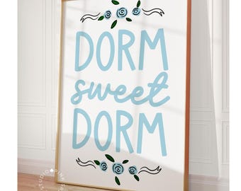 May include: A white poster with the text "Dorm sweet dorm" in light blue lettering. The text is surrounded by a decorative border of blue flowers and ribbons.