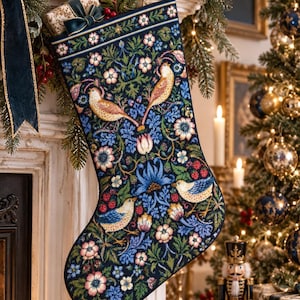 Könnte beinhalten: Ein dunkelblauer Weihnachtsstrumpf mit einem aufwendigen Stickmuster aus bunten Vögeln, blühenden Blumen und grünem Blattwerk. Der Strumpf verfügt über eine dekorative Bordüre am oberen Rand und eine Stoffschlaufe zum Aufhängen des Textilartikels.