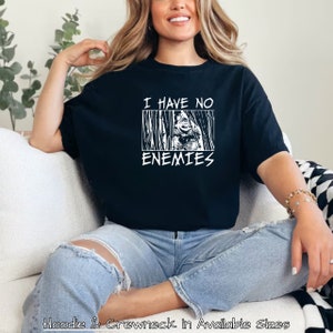 May include: A black t-shirt with a white graphic that says "I have no enemies" with a stylised image of a person behind bars.
