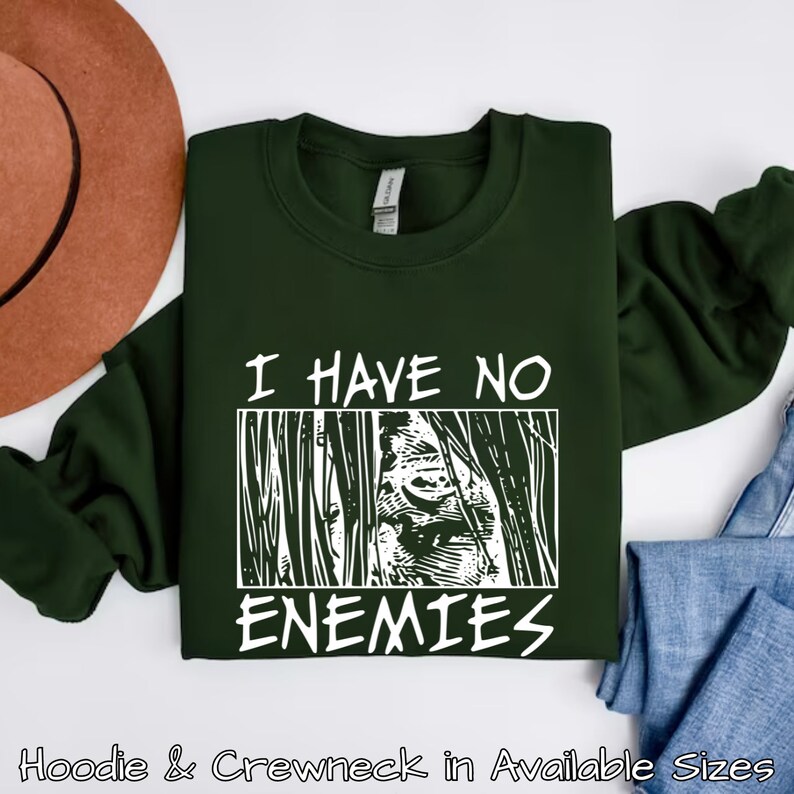 May include: A dark green sweatshirt with white text that reads "I have no enemies" and a graphic of a face behind bars.