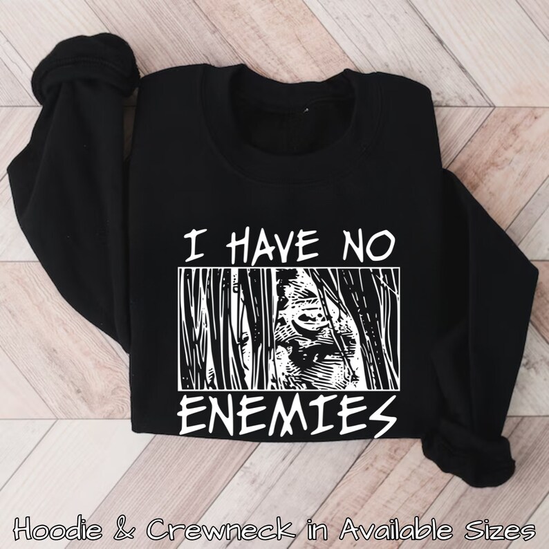 May include: Black sweatshirt with white text that reads "I have no enemies" and a graphic of a face behind bars.