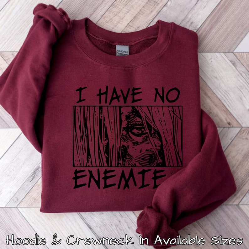 May include: Burgundy sweatshirt with black text that reads "I have no enemies" and a black and white graphic of a person's face with long hair.