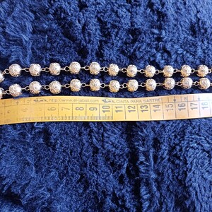 Pu&ograve; includere: Una collana a catena d'oro con perline rotonde e testurizzate. La collana &egrave; misurata con un metro a nastro, mostrando che &egrave; lunga circa 38 cm.