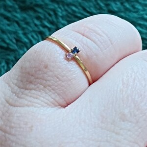 May include: A gold ring with two small gemstones, one blue and one pink.