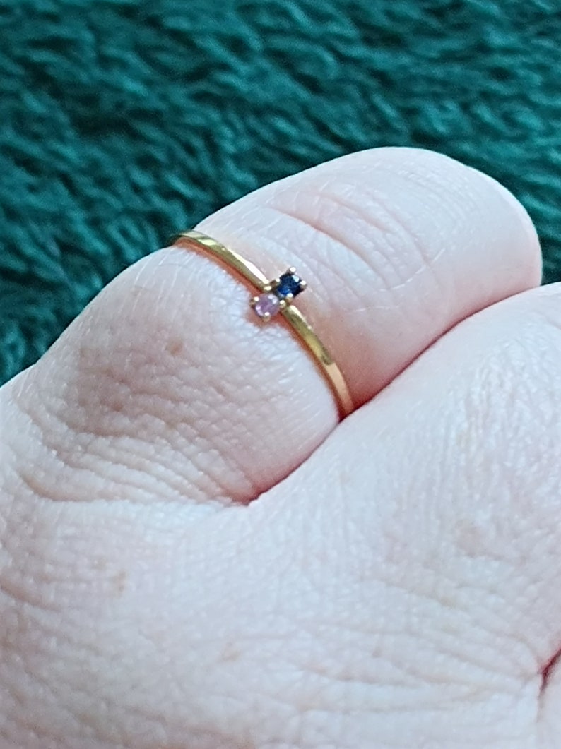 May include: A gold ring with two small gemstones, one blue and one pink.
