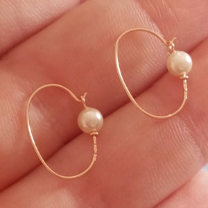 May include: A pair of gold hoop earrings with a single white pearl on each hoop.