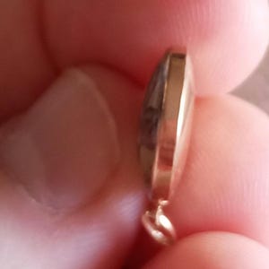 以下が含まれることがあります： 丸みを帯びたドーム型の金色のペンダント。ペンダントは滑らかで磨かれた表面で、チェーンを取り付けるための小さなループが上部に付いています。