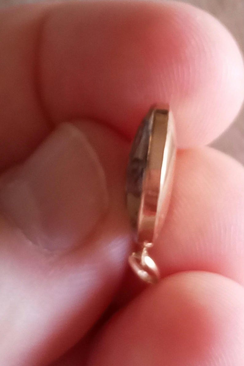 以下が含まれることがあります： 丸みを帯びたドーム型の金色のペンダント。ペンダントは滑らかで磨かれた表面で、チェーンを取り付けるための小さなループが上部に付いています。