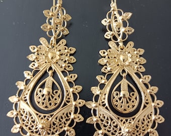 May include: A pair of gold filigree earrings with a teardrop design. The earrings are intricate and delicate, with a floral pattern.