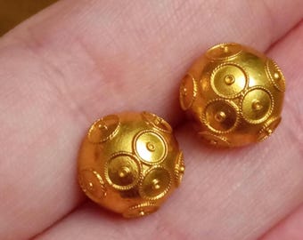 May include: A pair of gold earrings with a round, textured design. The earrings are made of small, circular shapes that are arranged in a pattern.