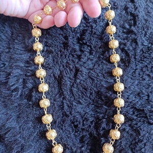 Pu&ograve; includere: Una collana d'oro con una catena fatta di piccole perle rotonde e con motivi.