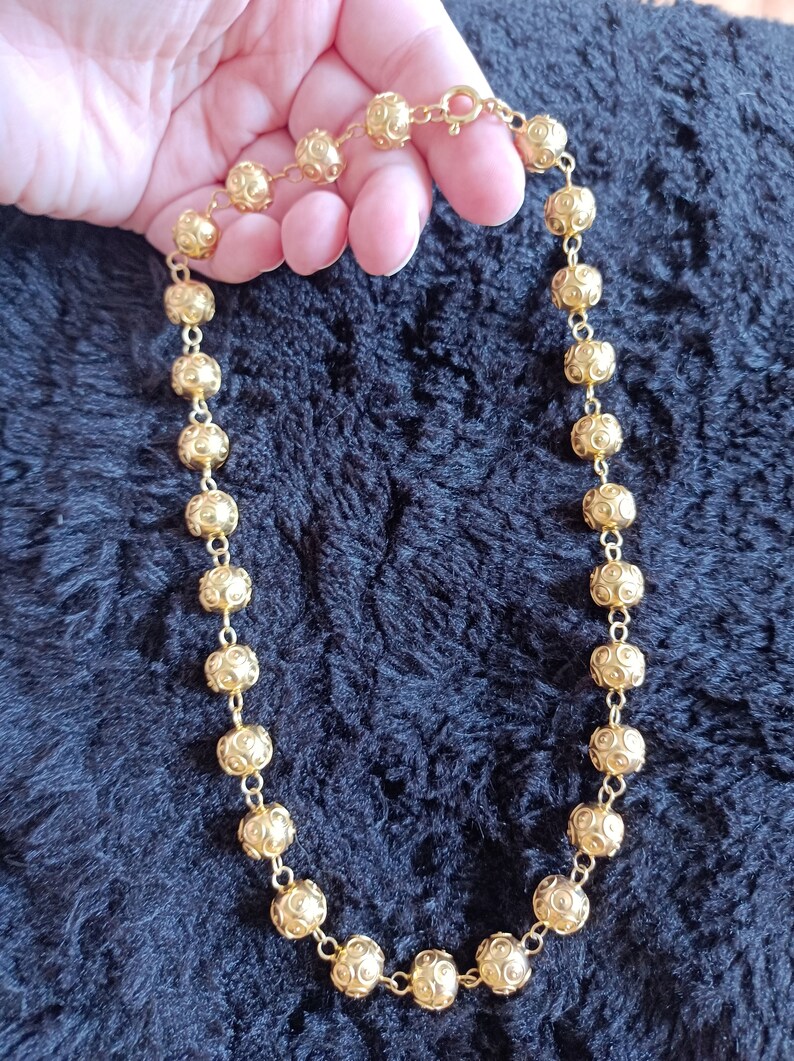Pu&ograve; includere: Una collana d'oro con una catena fatta di piccole perle rotonde e con motivi.