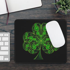 May include: A black mouse pad with a green shamrock design. The shamrock is made up of intricate swirls and lines.