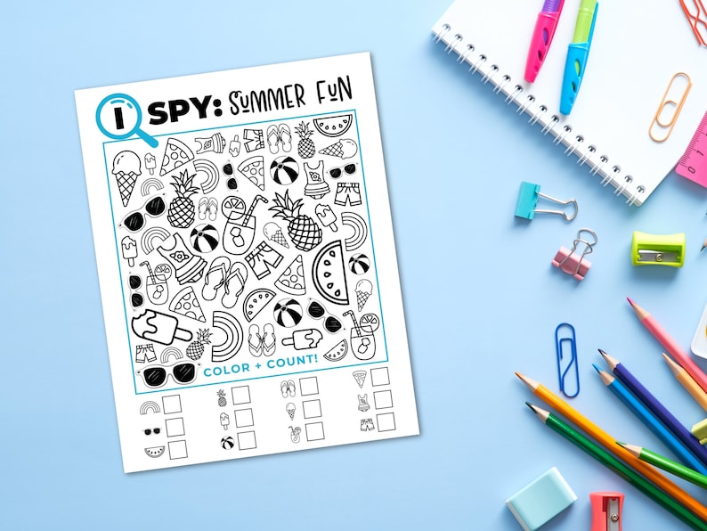 Puede incluir: Una hoja de actividades en blanco y negro "I SPY: SUMMER FUN" con ilustraciones de verano, incluyendo helados y gafas de sol. La hoja est&aacute; sobre una superficie azul claro, rodeada de &uacute;tiles escolares como l&aacute;pices y un cuaderno.