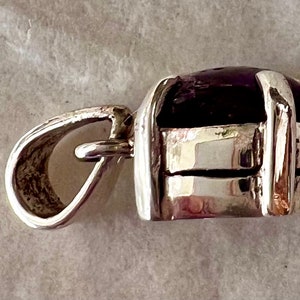 May include: A silver pendant featuring a dark purple gemstone set within a silver frame. The pendant has a loop for attaching to a chain.