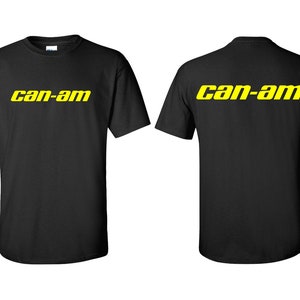 Puede incluir: Camiseta negra con el texto amarillo "can-am" impreso en la parte delantera y trasera. La camiseta es de cuello redondo y parece estar hecha de algod&oacute;n o un material similar. El texto est&aacute; en negrita, sin serifa.