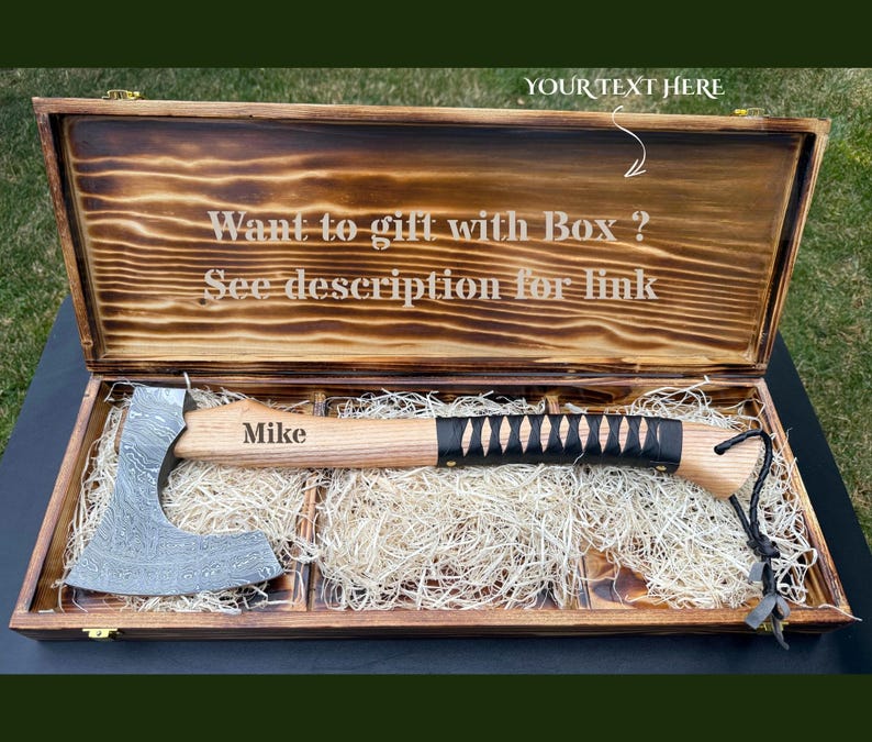 May include: A Damascus steel axe with a light wood handle, black leather wrap, and the name Mike engraved on the handle. The axe rests in a rectangular, burnt-finish wooden box with the text Want to gift with Box ? See description for link.