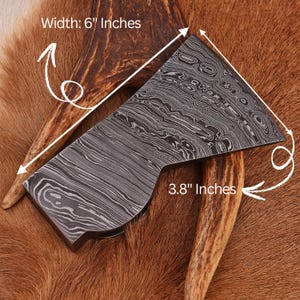 K&ouml;nnte beinhalten: Nahaufnahme eines kleinen Axtkopfes mit einer gemusterten Stahloberfl&auml;che. Der Axtkopf ist 6 Zoll breit und 3,8 Zoll hoch.