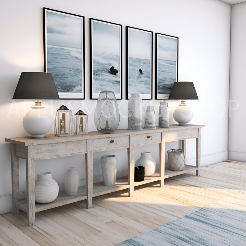 May include: A light wood console table with four drawers and two shelves. The table is decorated with a variety of items, including lamps, vases, and framed pictures. The pictures are of a beach scene with waves crashing on the shore.