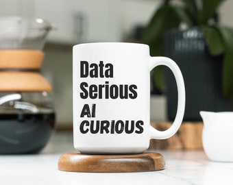 May include: White ceramic mug with black text that reads "Data Serious AI Curious". The mug is sitting on a wooden coaster.