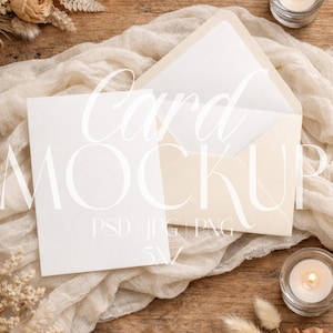 May include: A card mockup with a white card and envelope, draped on a cream-colored fabric. The text "Card MOCKUP" is overlaid on the card. The scene includes candles, dried flowers, and a wooden surface.