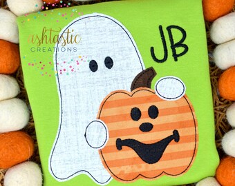 May include: A lime green shirt featuring a white ghost and an orange pumpkin with a smiling face. The shirt has the initials "JB" in black. The shirt is surrounded by orange and white decorative balls.