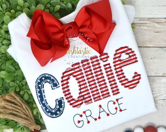 May include: White onesie with a red bow. The onesie has a red, white, and blue embroidered design that says "Callie Grace" with stars.