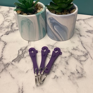 以下が含まれることがあります： 黒い持ち手と「But First, Coffee」の文字が黒い手書き風フォントで書かれた白いセラミックマグ。マグカップは白い表面に置かれています。