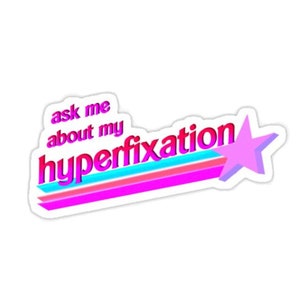 Op de afbeelding: Een sticker met de tekst "ask me about my hyperfixation" in een retro lettertype. Het woord "hyperfixation" is roze, met een blauw en roze spoor en een paarse ster.