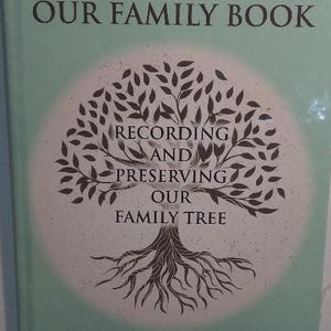 K&ouml;nnte beinhalten: Ein gr&uuml;nes Buch mit dem Titel "Our Family Book" und einer stilisierten Baumillustration. Der Text unter dem Baum lautet "Recording and Preserving Our Family Tree" und "From Generation to Generation".