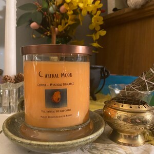 May include: A 11 oz. natural soy wax candle in a clear glass jar with a copper lid. The candle is labeled "Astral Moon Gemini - Mystical Romance".