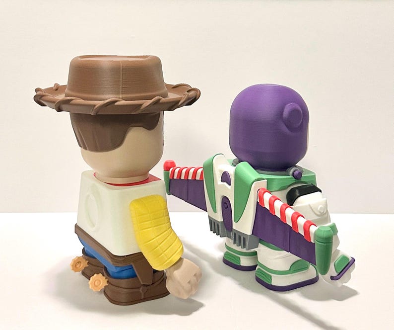 May include: Two 3D-printed toy figures: Woody, a cowboy with a brown hat, and Buzz Lightyear, a space ranger with a purple helmet and green and white wings. The toys are colorful and detailed, perfect for collectors or fans of the movie.