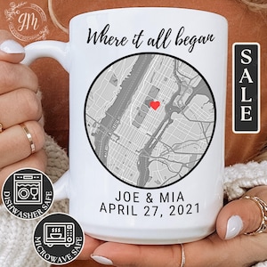 May include: White ceramic mug with a black and gray map design and the text "Where it all began" and "Joe & Mia April 27, 2021". The map has a red heart in the center. The mug is dishwasher and microwave safe.