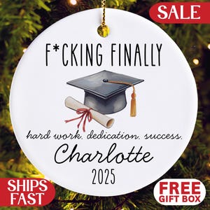 May include: White ceramic graduation ornament with the text "F*CKING FINALLY" and "hard work, dedication, success." Features a graduation cap, diploma, and the name "Charlotte 2025". Includes "SALE", "SHIPS FAST", and "FREE GIFT BOX" text.