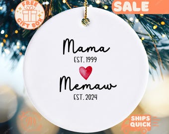Può includere: Ciondolo in ceramica bianca con testo nero che recita "Mama Est. 1999" e "Memaw Est. 2024" con un cuore rosso in mezzo.