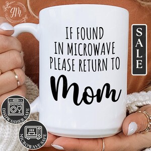 May include: White ceramic mug with the text "IF FOUND IN MICROWAVE PLEASE RETURN TO Mom" in black. The mug has a white handle and is dishwasher and microwave safe. A "SALE" sticker is visible.
