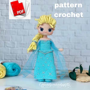 Könnte beinhalten: Handgefertigte Häkelpuppe in einem hellblauen Kleid mit Sternenmuster, blonden Haaren und blauen Augen. Die Puppe hat einen langen Zopf und trägt einen transparenten blauen Umhang. Der Text "english pattern crochet" ist enthalten.