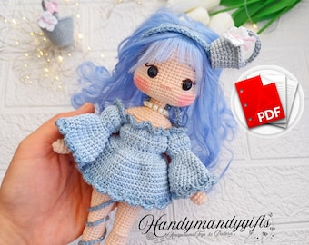 Könnte beinhalten: Häkelpuppenmuster im PDF-Format. Die Puppe trägt ein blaues Kleid und hat blaue Haare. Die Puppe hält eine kleine Gießkanne. Das Muster ist auf Etsy zum Kauf erhältlich.