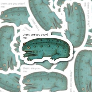 Die-cut matte vinyl sticker featuring a green frog with the text 'Them: Are you okay? Me:' inspired by medieval marginalia.